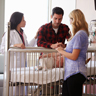 Parents stand beside crib