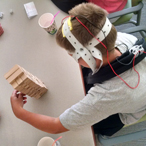 Boy fitted with brain stimulation headgear used in the study manipulates blocks.