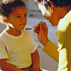 Young boy being spoon-fed medicine