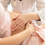 physician’s hands on a pregnant woman’s abdomen