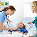 Hospital staff attend to a child in bed in the pediatric intensive care unit, while the child’s mother stands by the bed