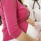 A pregnant woman stands next to a healthcare provider filling out a form.