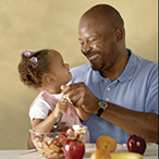 Man sharing healthy food with little girl.