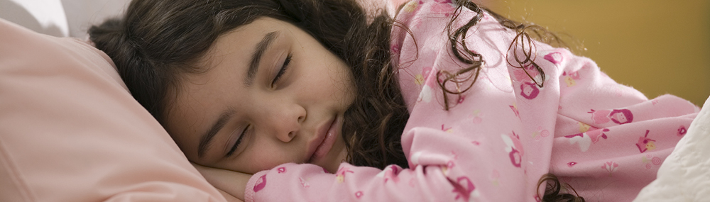 A young girl asleep in bed.