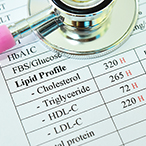 A stethoscope rests on top of a listing of the different kinds of cholesterol.