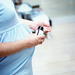 Pregnant woman taking pills out of a bottle.