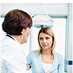 Medical professional with pen and clipboard talking with woman who looks concerned.