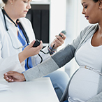 A female doctor takes the blood pressure of a pregnant woman.