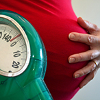 Pregnant woman holding belly with her hand.