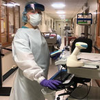 Nurse in protective gear in hospital hallway.