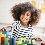 Preschool age child playing with blocks at a desk.