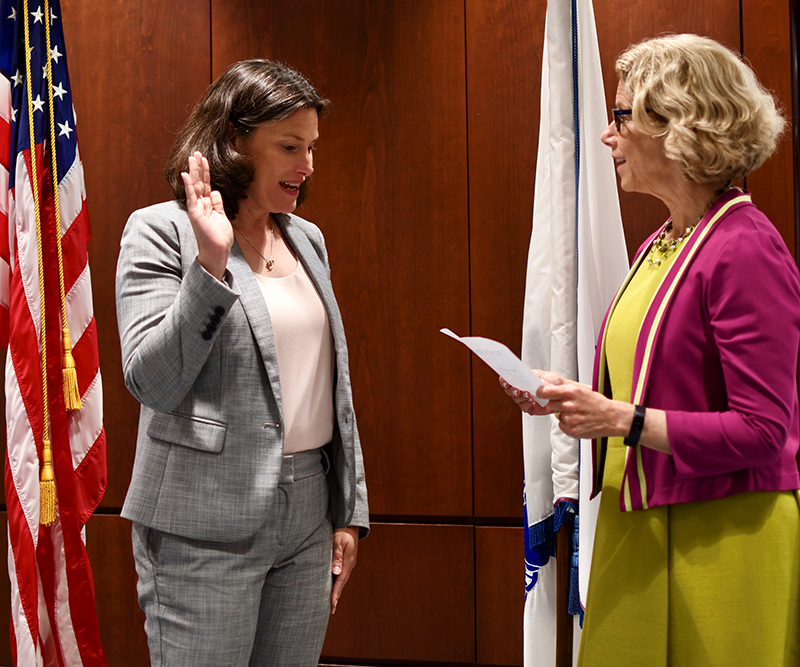 Dr. Cernich raises her right hand while Dr. Diana W. Bianchi, NICHD Director, reads from a piece of paper.