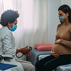 Pregnant woman in a healthcare provider’s office talking with the doctor.