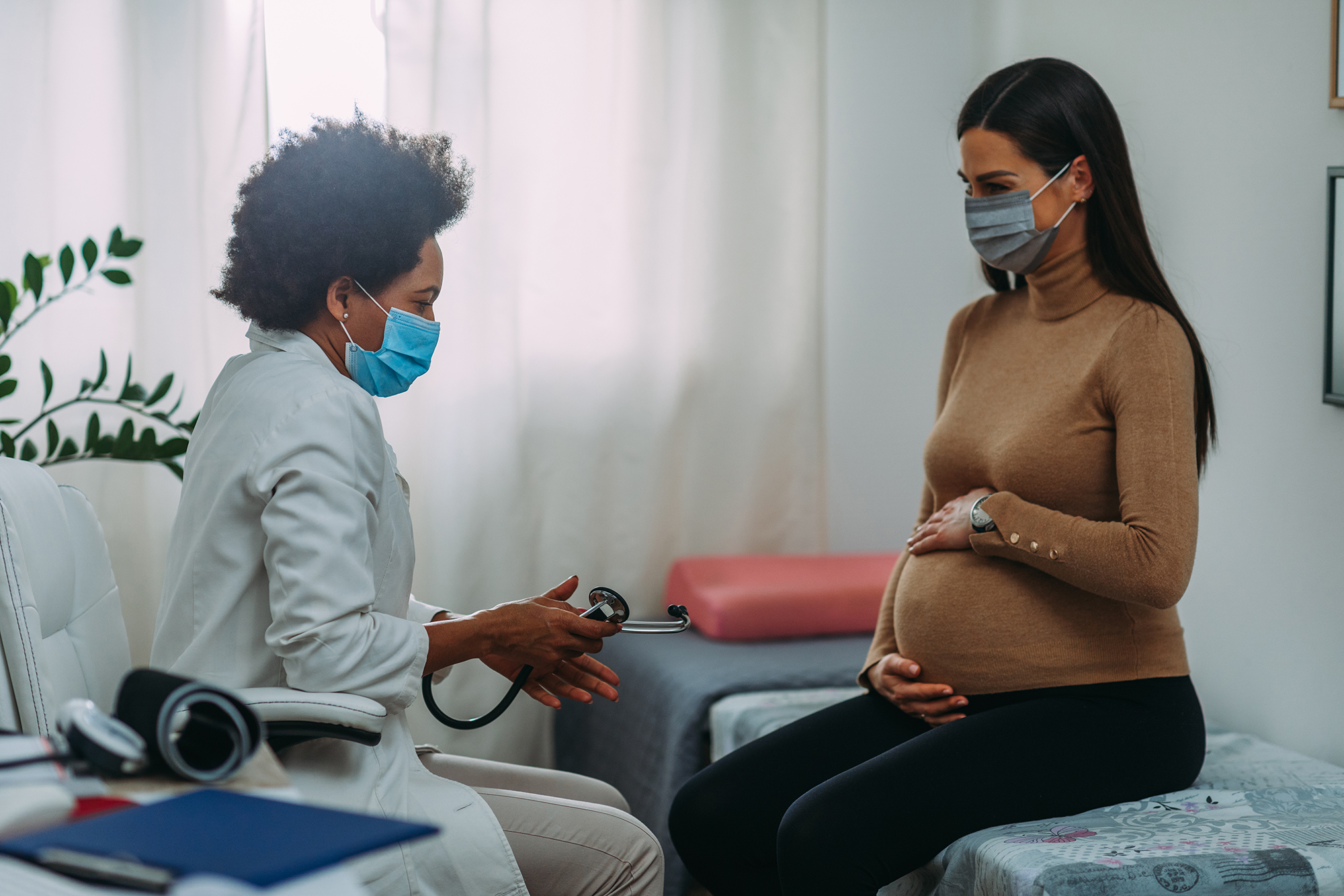 Pregnant woman in a healthcare provider’s office talking with the doctor.