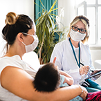 Woman holding infant and talking with healthcare provider.