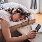 Woman lying in bed looking at cell phone.