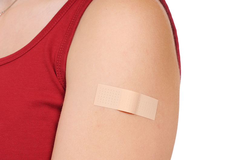 Woman wearing a red shirt with a band-aid on her upper arm.