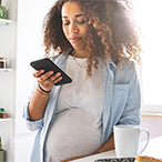 Pregnant person holding a mobile device.