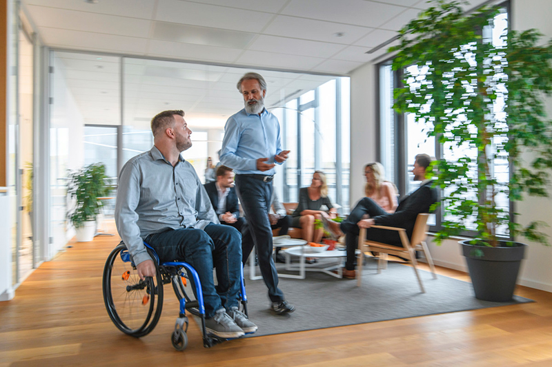 Person in wheelchair talking to standing healthcare worker.