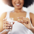 Pregnant woman holding a clear medicine/nutrition capsule.