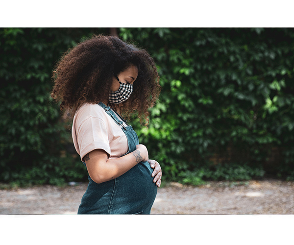 Pregnant woman outside wearing a mask.