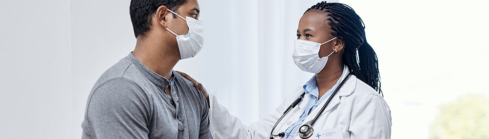 A man speaking with a healthcare provider. Both are wearing masks.