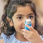 Child holding inhaler for asthma treatment.