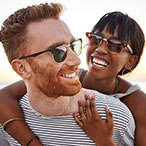 A man and woman are laughing along the beach.