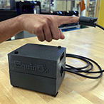 The EquinOx device is attached to a pulse oximeter, which is attached to someone’s finger. 