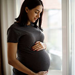 Pregnant person with hands on abdomen.