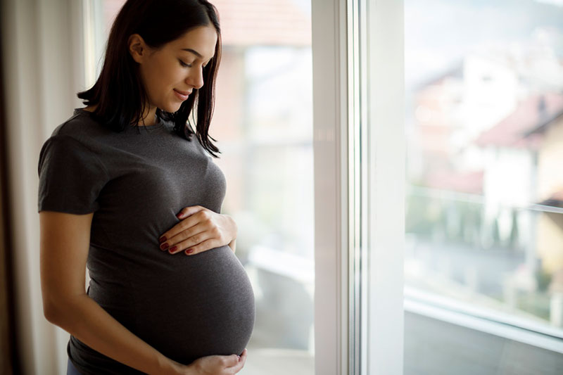 Pregnant person with hands on abdomen.