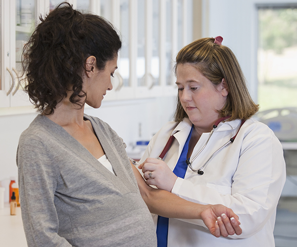 A healthcare provider takes blood from the inner arm of a pregnant person.