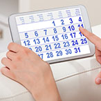 Woman pointing to a calendar on a tablet device.