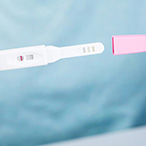 Hands holding a dipstick pregnancy test.