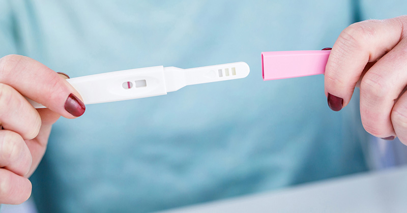 Hands holding a dipstick pregnancy test.