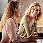 Four women sitting at a table talking and laughing.