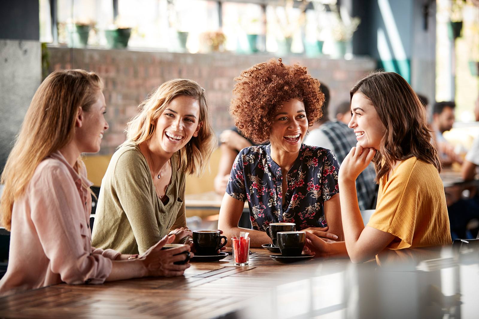 Four women sitting at a table talking and laughing.