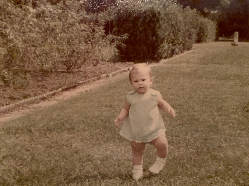 Dr. Cernich’s bowlegged feet are visible as she walks across a grassy field. 