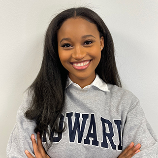 A young woman wearing a “Howard” sweater smiles against a white background.