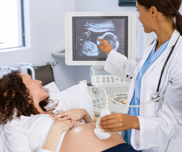 Image of a pregnant woman receiving an ultrasound from a technician. 