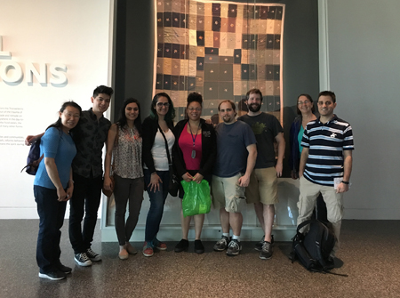 Lab members gather in front of a mounted tapestry in the African American History Museum.