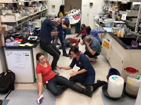 Lab members dressed as Star Trek characters, collapsed on the floor of the lab as a cartoon ghost cutout attacks from the doorway.