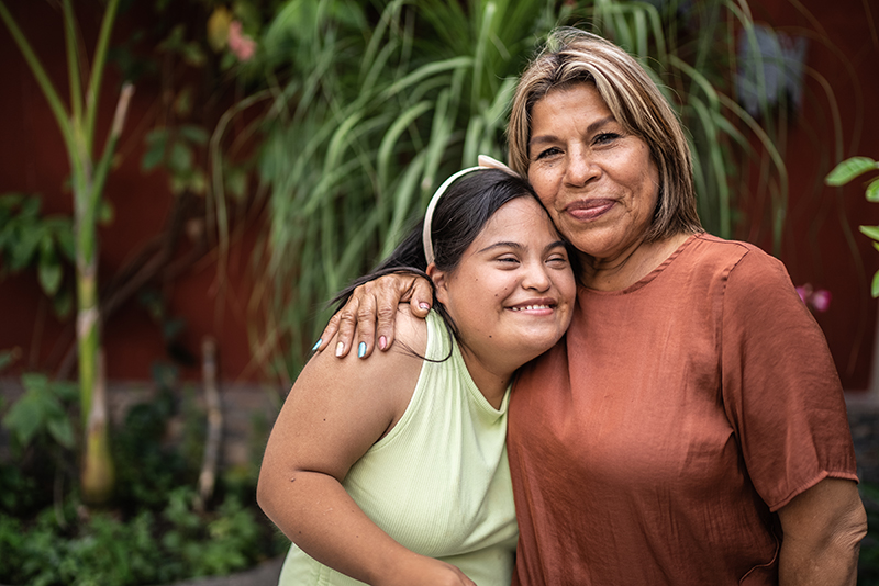 Older woman hugging a young girl with Down syndrome.