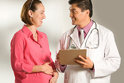A pregnant woman smiling and talking to a healthcare provider.