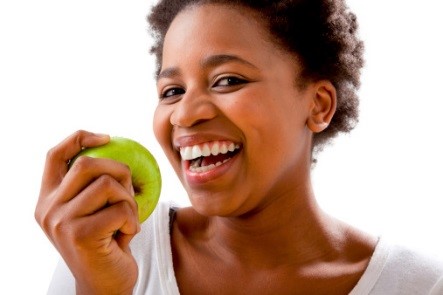 Woman smiling as she prepares to eat an apple.