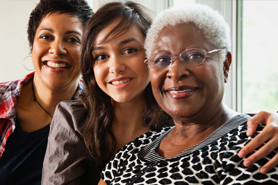 Three smiling women who are from different generations with a family.