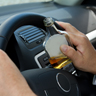 Hands holding car steering wheel while clutching liquor bottle.